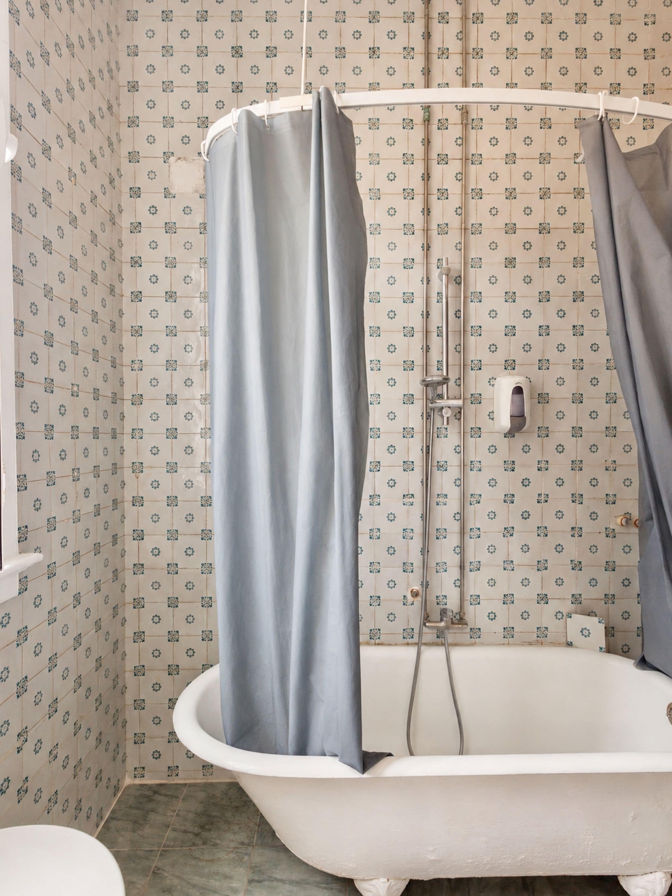 Een badkamer met een bad, douchegordijn en betegelde wanden.