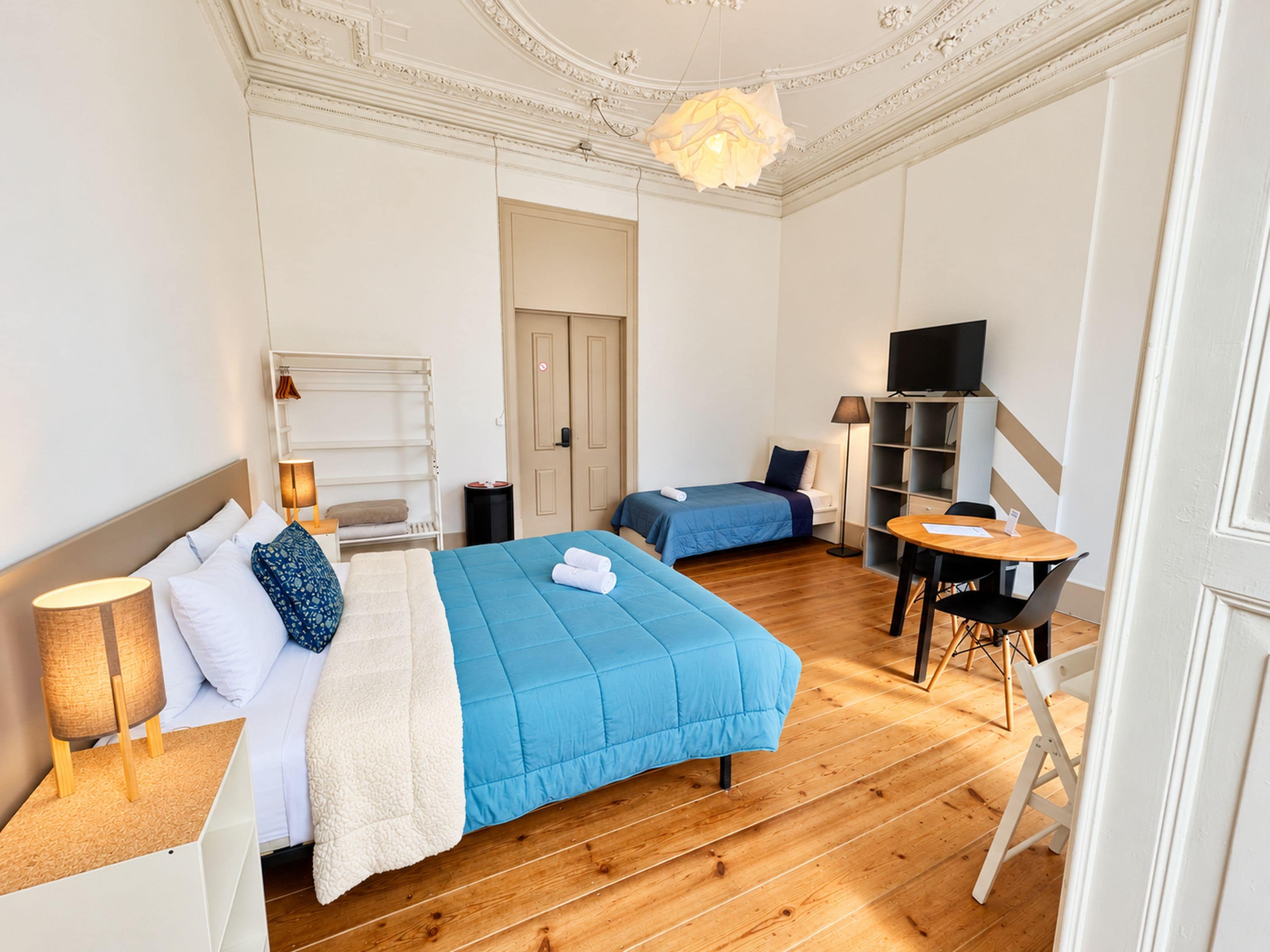 A hotel room with two beds, a desk with a chair, a television, and a small table.