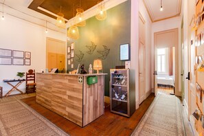 A reception area with a wooden desk, a glass display case, and a wall-mounted QR code. - Ambiente Hostel (Lisbon)