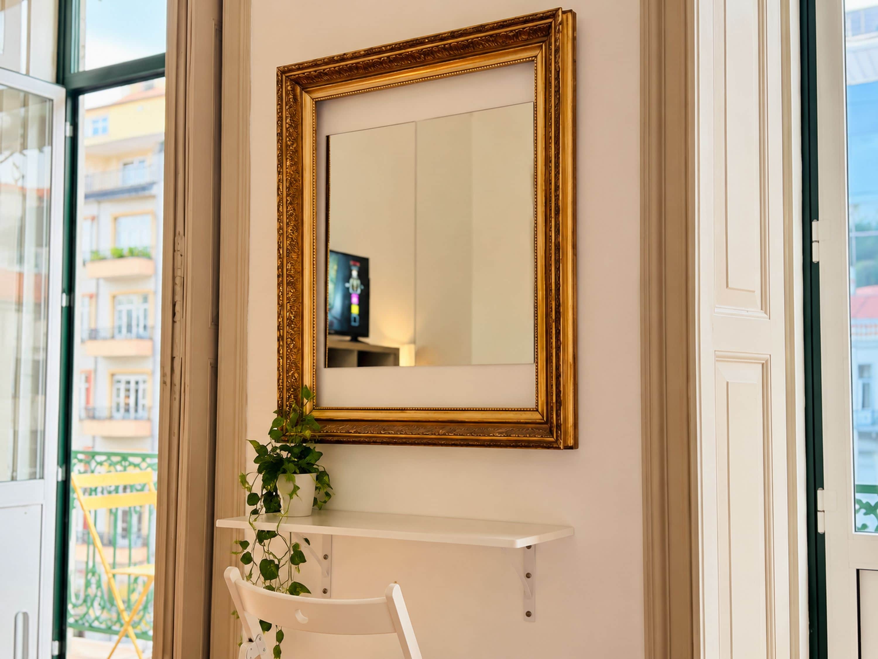 Ein Zimmer mit einem großen Spiegel an der Wand, einer Zimmerpflanze und einem weißen Stuhl.