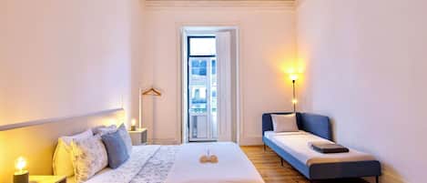 A bedroom with a bed, bedside table, lamp, and a small sofa.