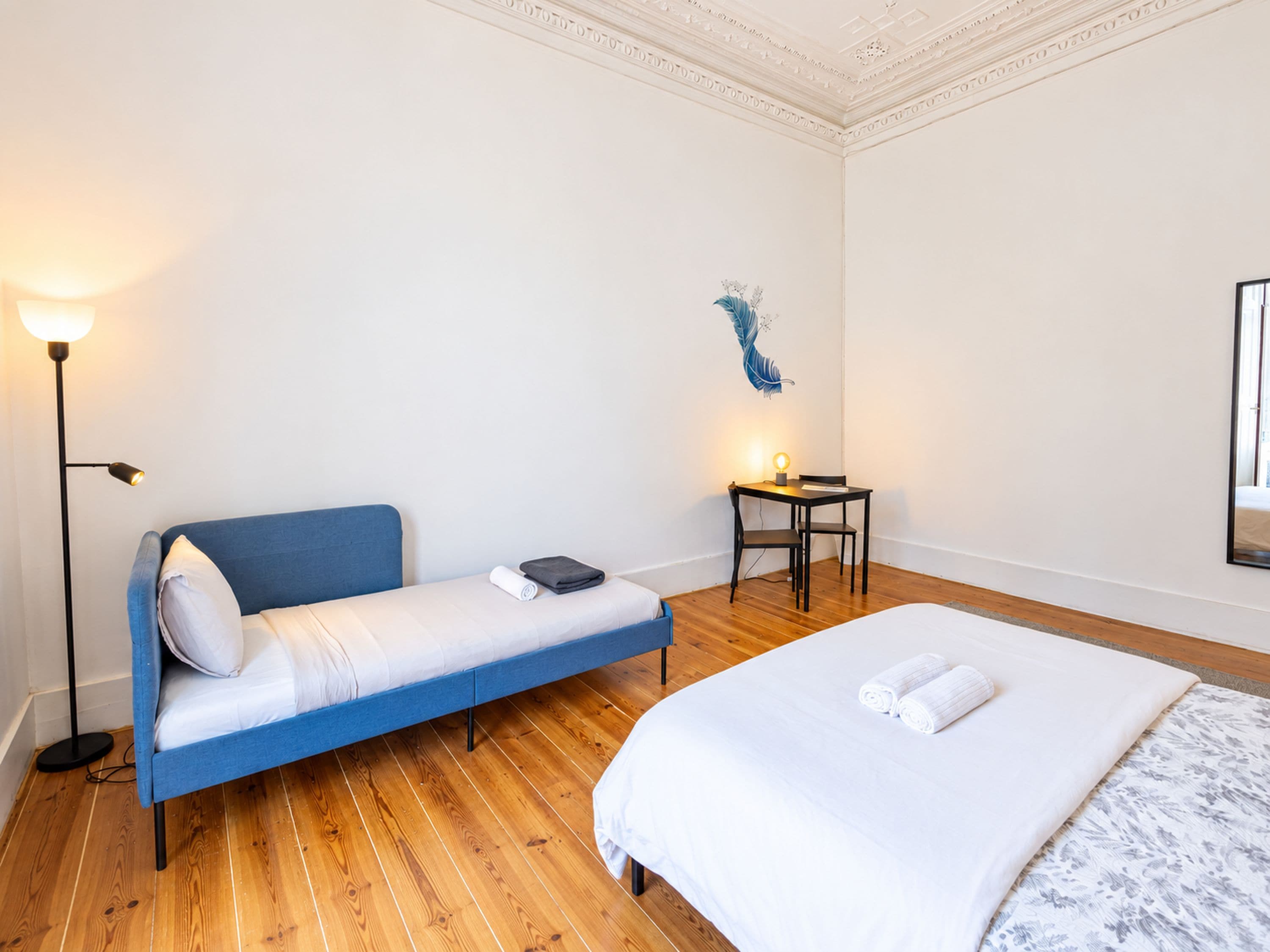 Un dormitorio con una cama individual, un escritorio, una silla y una lámpara de pie.