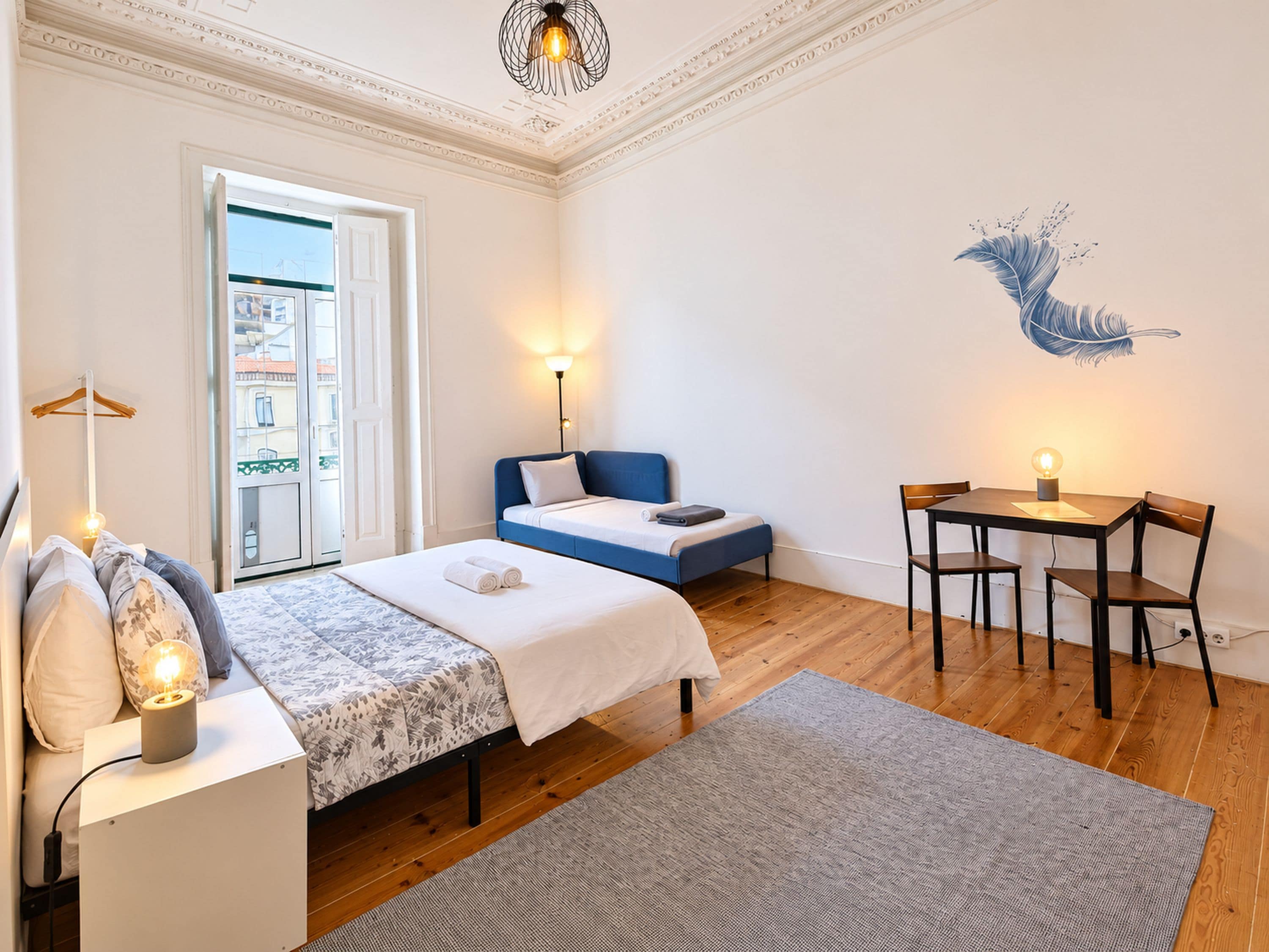 Une chambre d’hôtel comprenant un lit, un bureau, une chaise, une lampe et un élément décoratif mural.