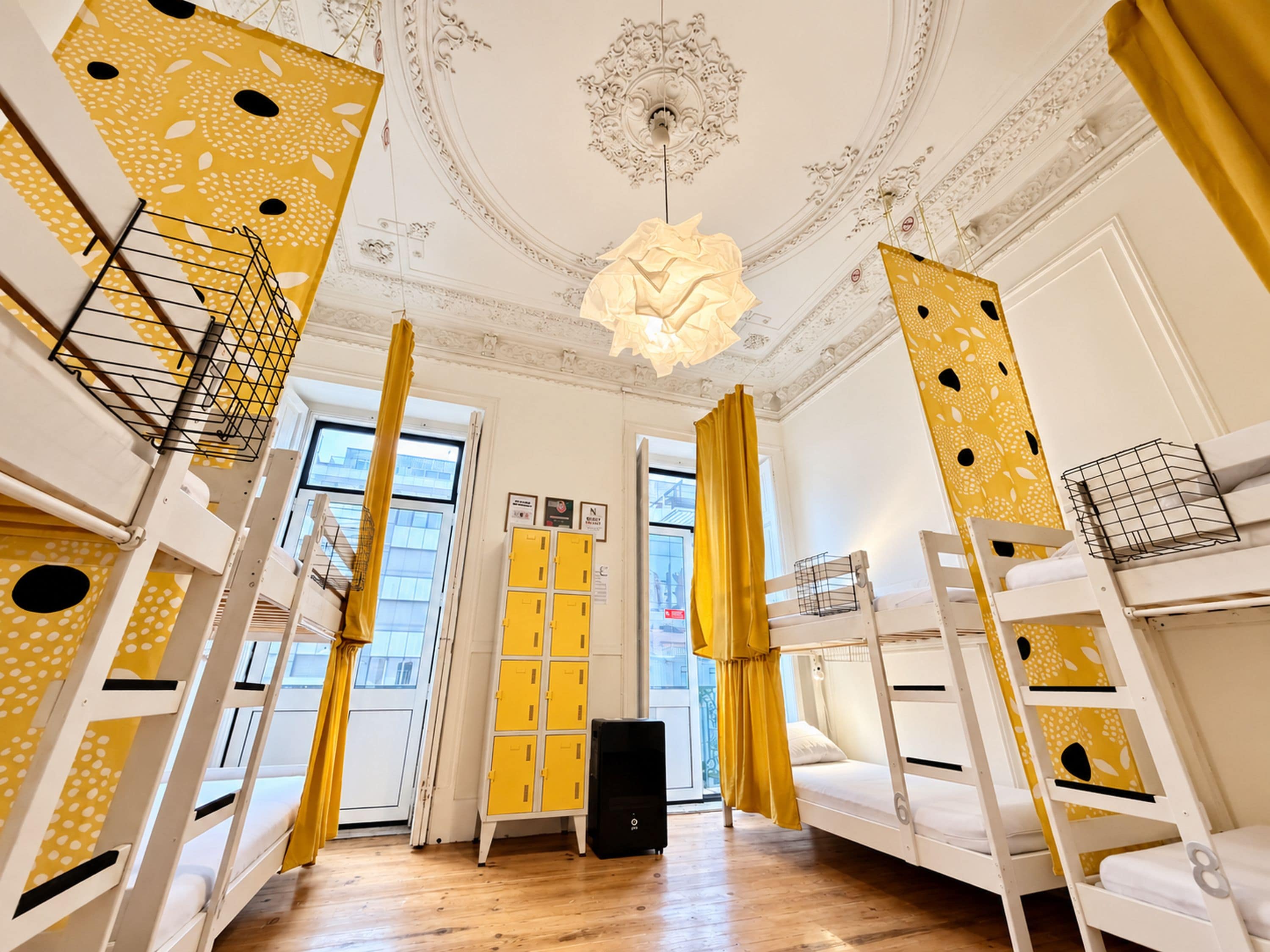 Una habitación con literas, un mueble de almacenamiento amarillo y un techo blanco con diseños intrincados.