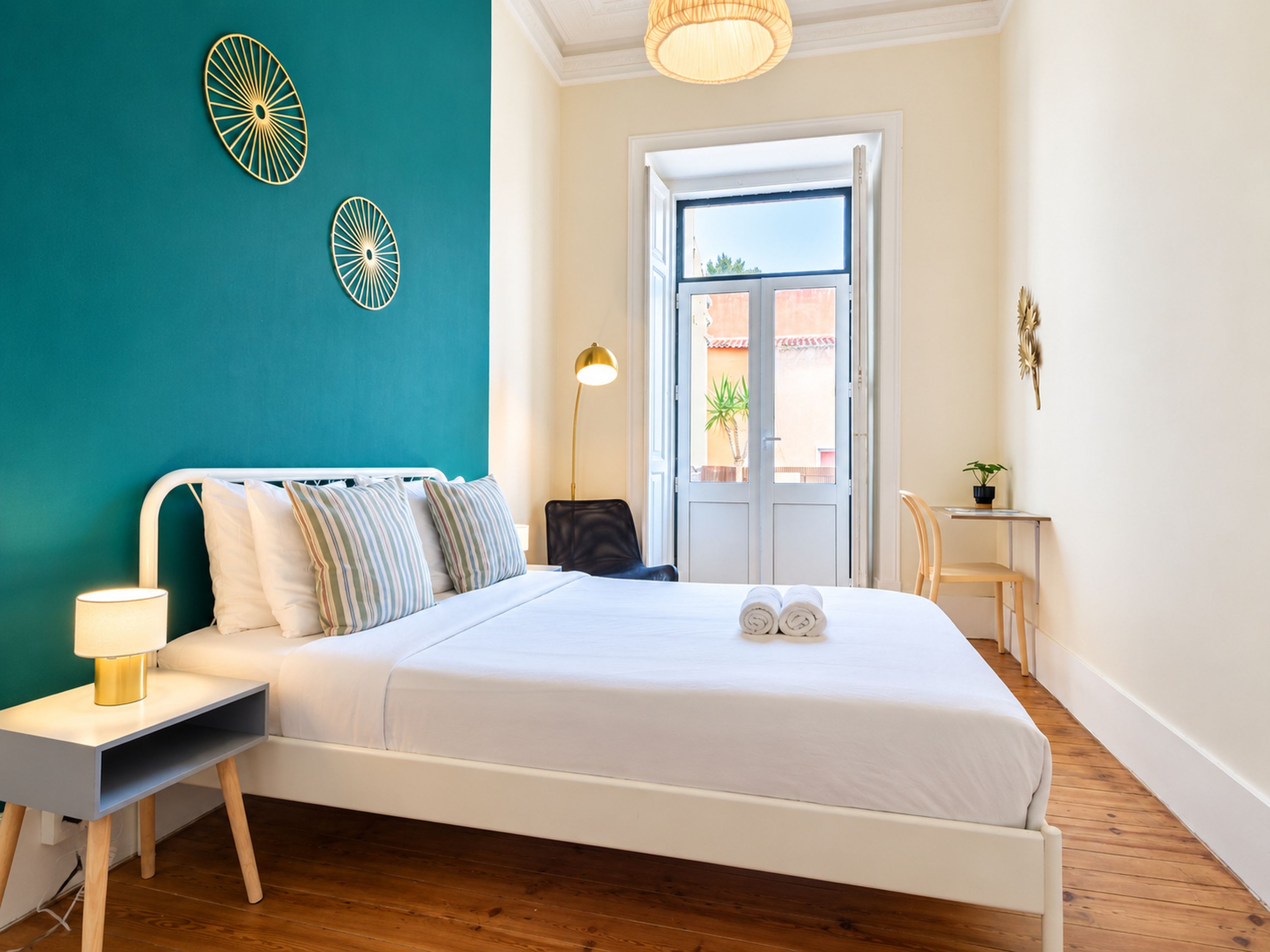 Habitación de hotel con cama, lámpara de noche y vistas a través de una puerta.