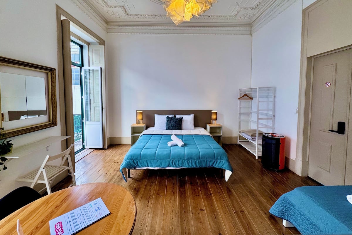 Une chambre d’hôtel comprenant un lit, des tables de chevet, une armoire, un miroir et un lustre.