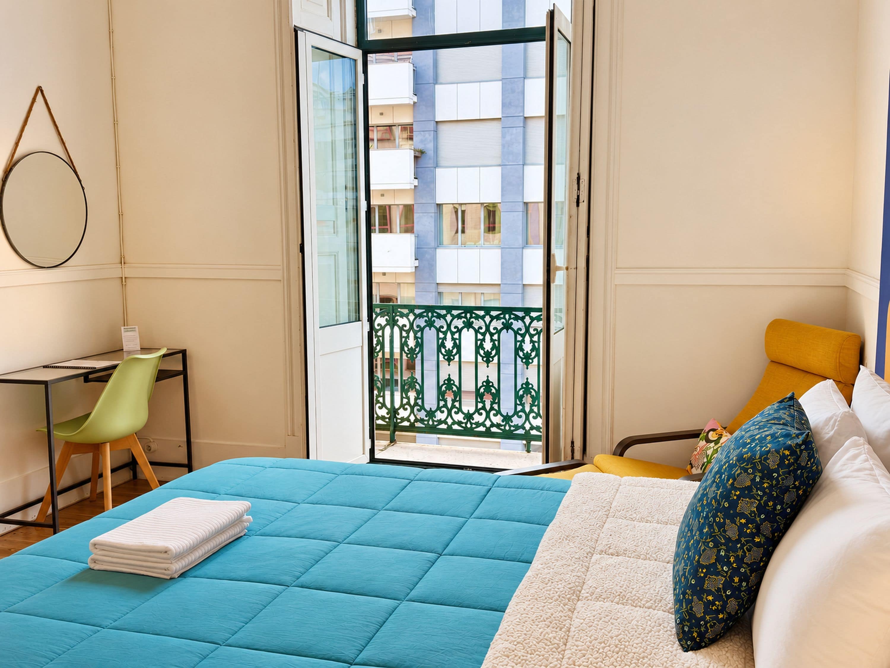 Een slaapkamer met een bed, een bureau, een stoel en een balkon.