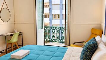 Een slaapkamer met een bed, een bureau, een stoel en een balkon.