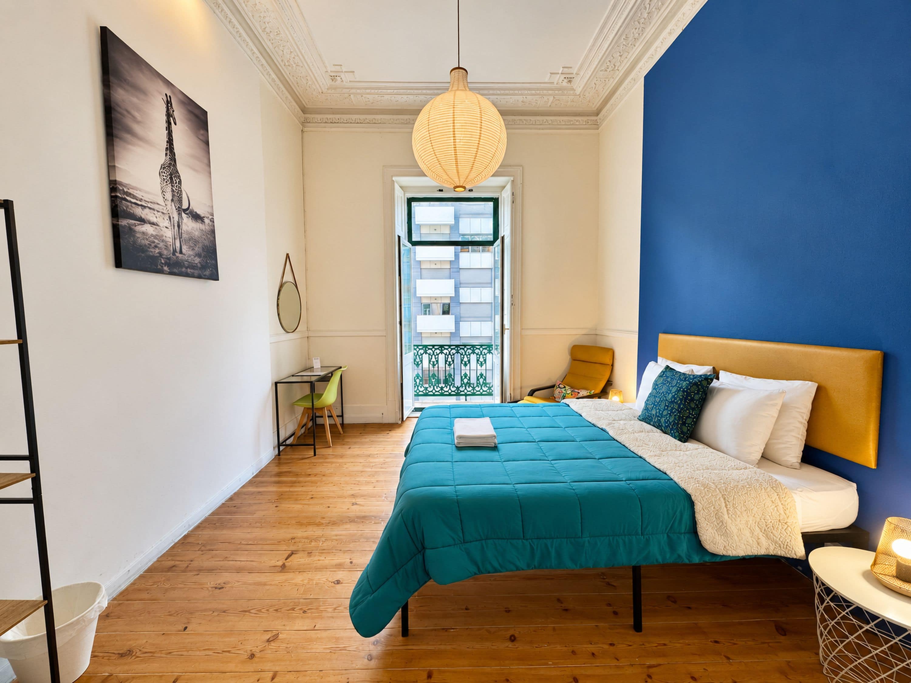 A bedroom with a bed, a desk, a chair, a window, and a door.