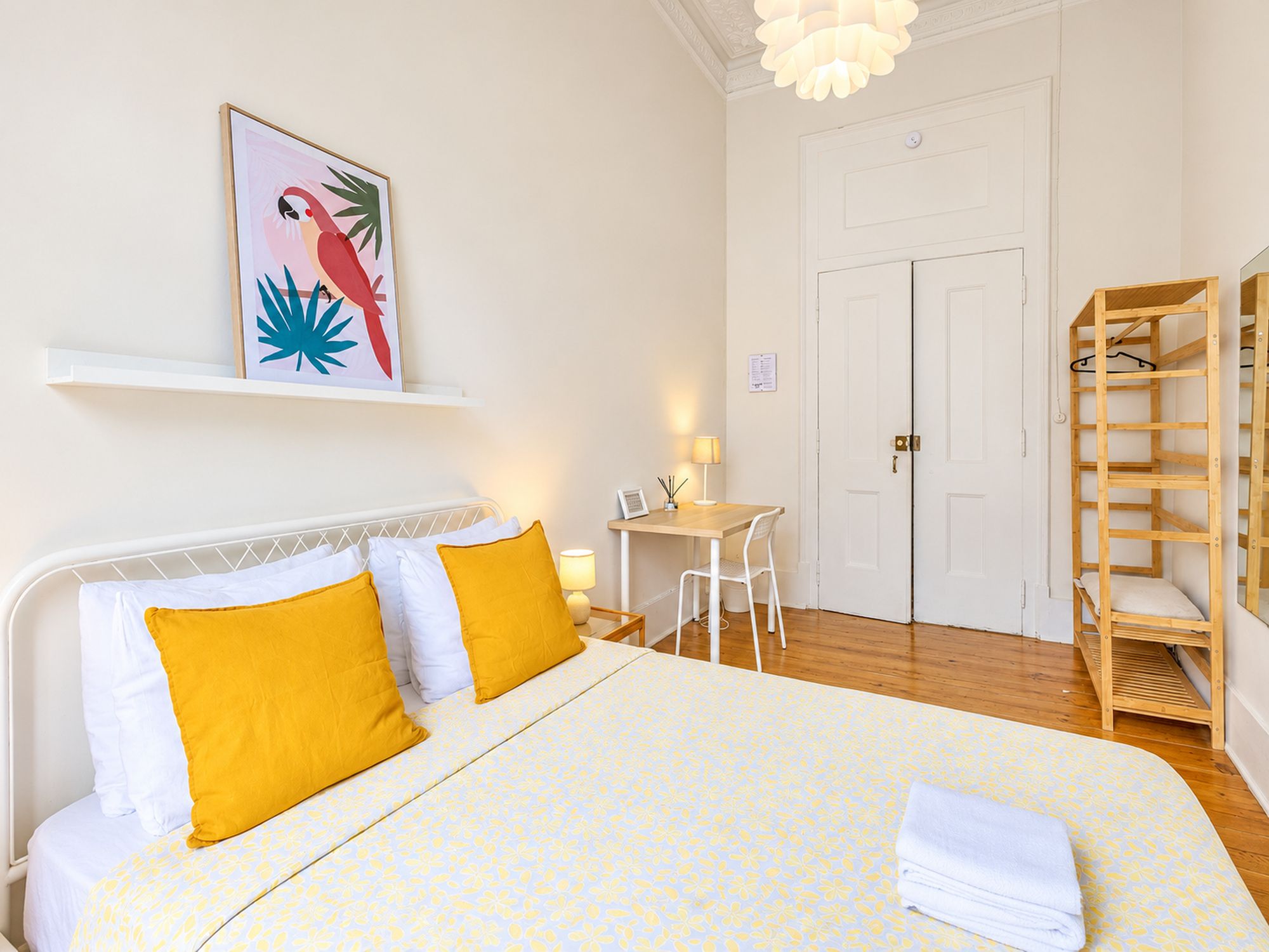 Habitación de hotel con cama, escritorio, silla, armario y un cuadro en la pared.