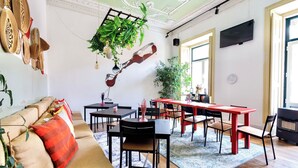 A modern living room with a sofa, dining table, chairs, and a hanging plant. - Ambiente Hostel (Lisbon)