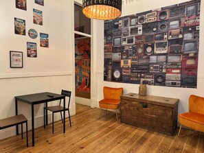 A dining area with a table, chairs, and a wall decorated with vintage radios. - Ambiente Hostel (Lisbon)