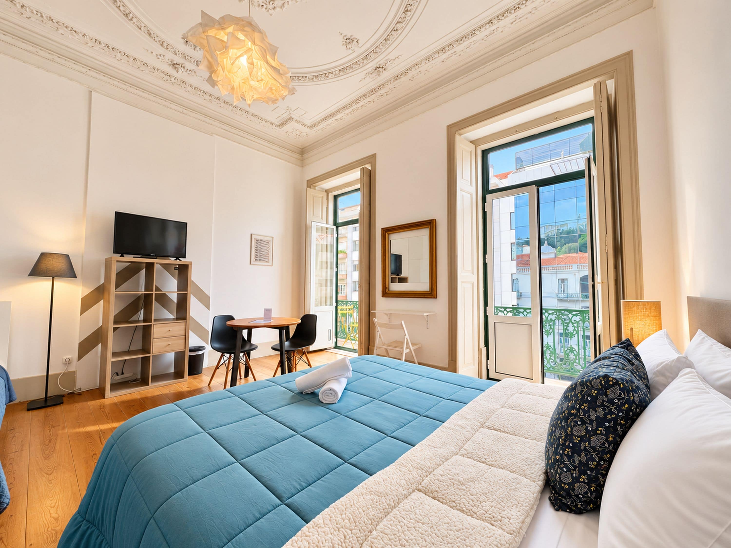 Een hotelkamer met een bed, een bureau, een stoel, een televisie en een balkon met uitzicht.