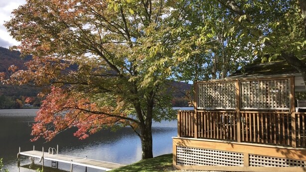 A lakeside property with a dock, a wooden deck, and a large tree with autumn foliage. - Vermont lake house,Vermont get away, come and relax (Elmore)