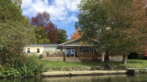 A lakeside cabin with a deck, surrounded by trees and a stone wall. - Vermont lake house,Vermont get away, come and relax (Elmore)