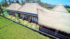 A traditional house with thatched roofs, a swimming pool, and a well-maintained garden. - Junjungan Serenity Privite Villa, Spa & Pool (Ubud)