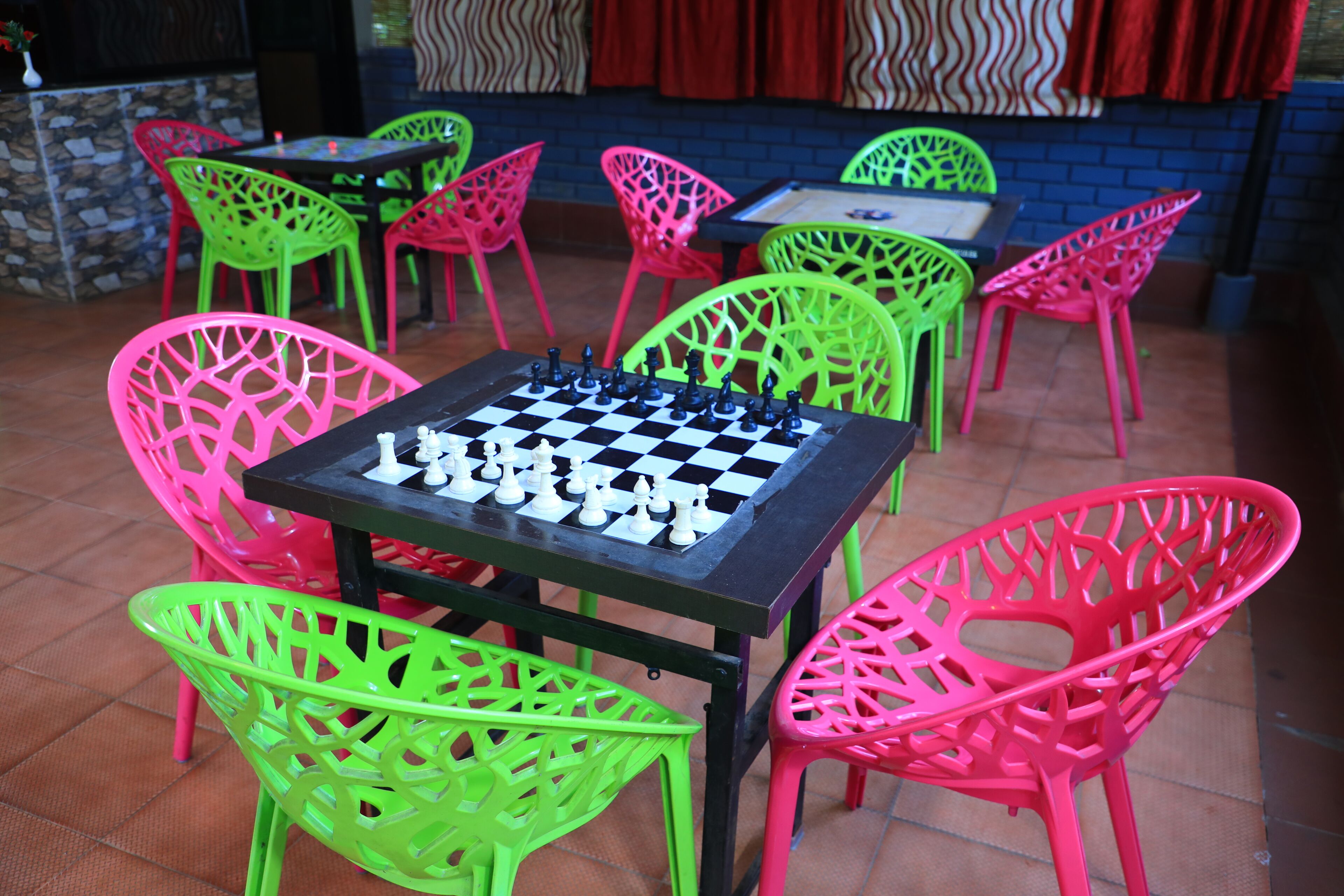 A chessboard set on a table surrounded by colorful chairs.