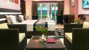 Une chambre d’hôtel comprenant un lit, deux fauteuils, une table basse et un téléviseur.