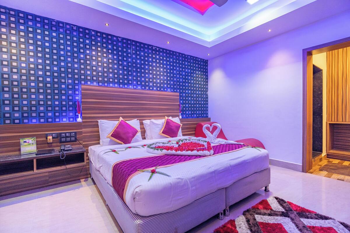 Un dormitorio moderno con una cama grande, cabecera de madera y pared con estampado.