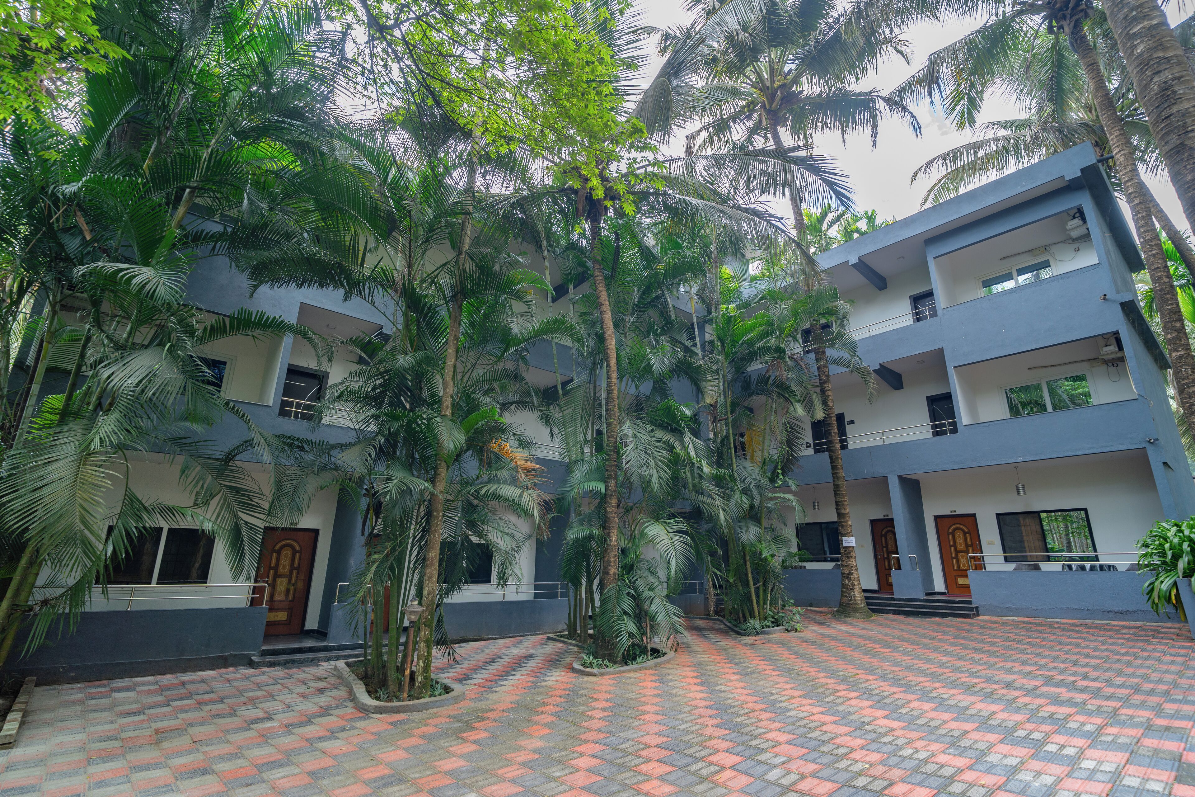 A multi-story building with a tiled courtyard surrounded by palm trees.