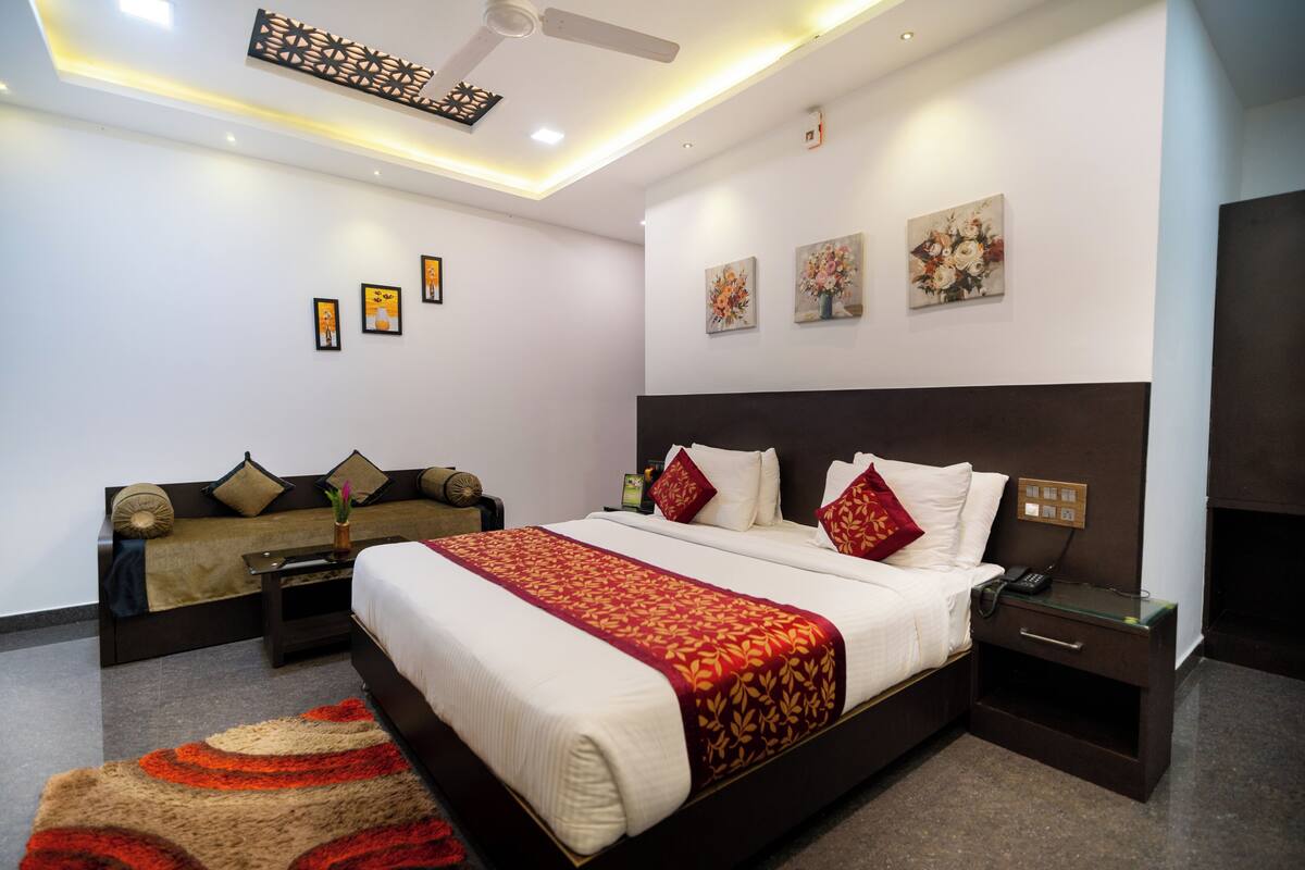 Una habitación de hotel moderna con una cama grande, un sofá, un escritorio y un ventilador de techo.