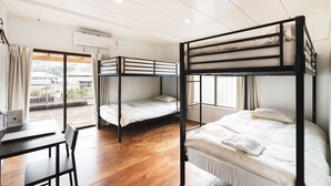 Une chambre de dortoir avec des lits superposés, un bureau et un ordinateur portable.