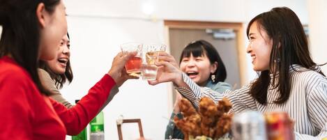 A group of people toasting with drinks at a table with food and condiments.