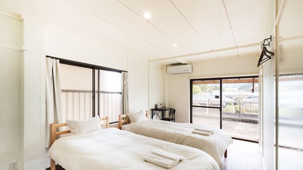 Une chambre d’hôtel avec deux lits, une petite table et une vue sur l’extérieur.