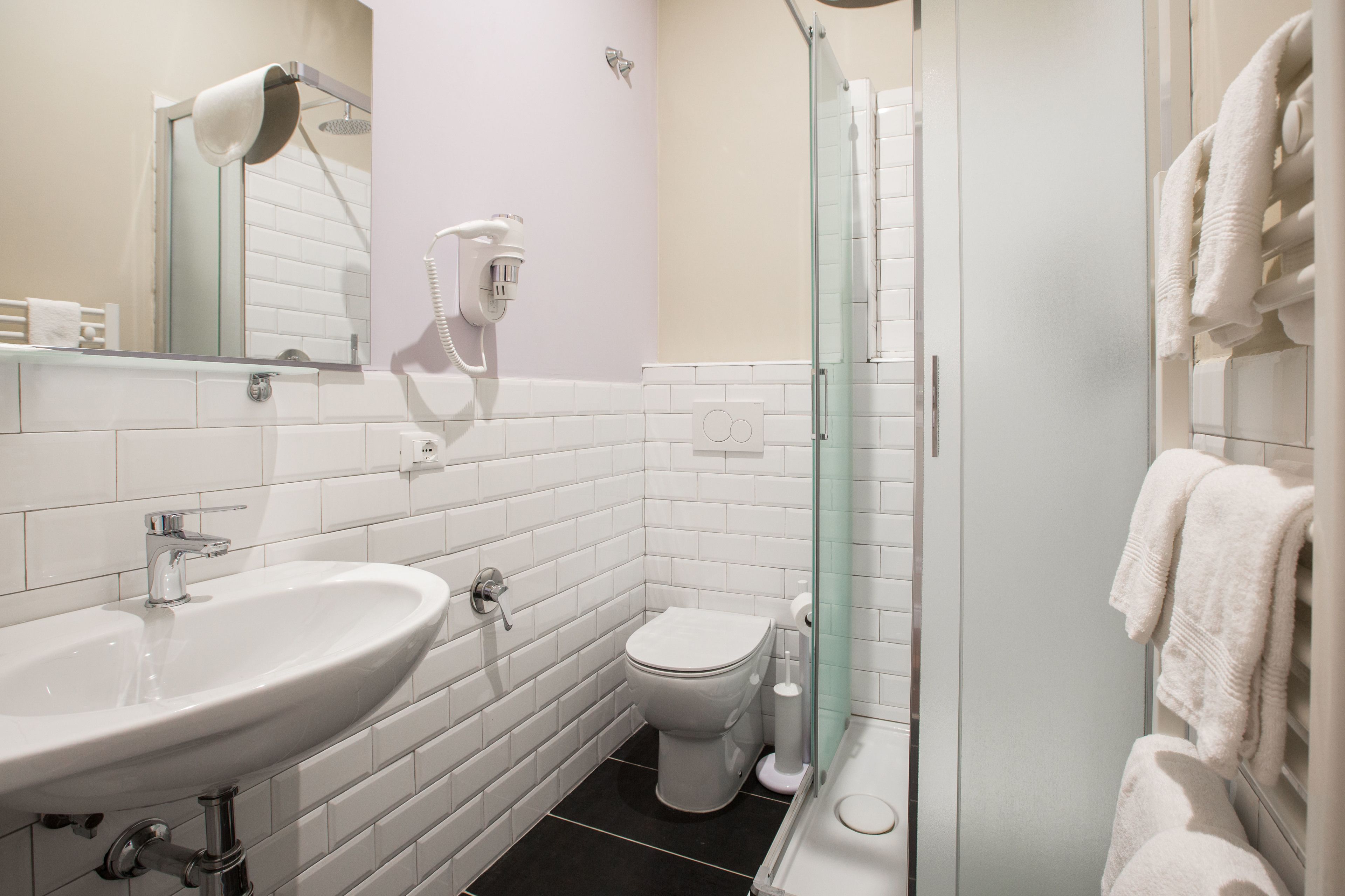 A modern bathroom with a white sink, toilet, and glass shower enclosure.