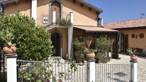 Edificio de estilo mediterráneo con un patio central, que cuenta con un balcón, plantas en macetas y un tejado de tejas.