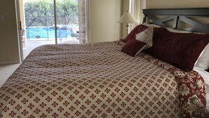 Un dormitorio con cama, vista a una piscina a través de un ventanal corredero y un cuadro en la pared.