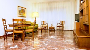 A well-furnished living room with a dining set, a sofa, a TV, and a cabinet. - Rosa Garden B&B (Mestre)