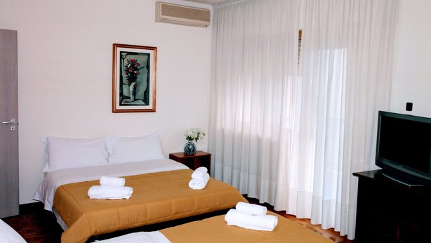 A hotel room with two beds, a television, and a painting on the wall. - Rosa Garden B&B (Mestre)