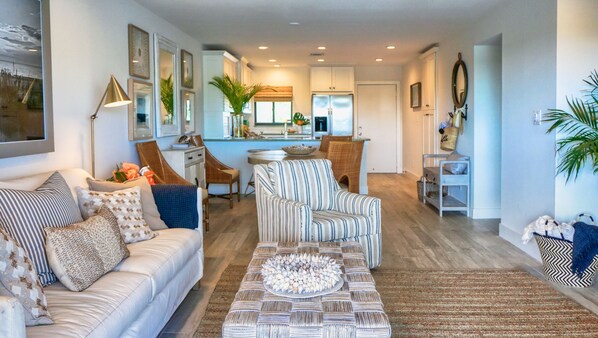 You're viewing the living room through to the front entry door and kitchen from the balcony doorway in this photo.