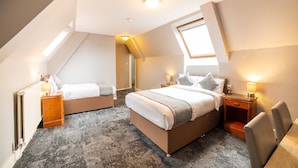 A modern hotel room with a sloped ceiling, two beds, a large window, and a view of the sky. - Royal Hotel (Kettering)