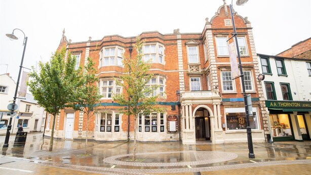 A historic building with a corner entrance, large windows, and a prominent entrance with a canopy. - Royal Hotel (Kettering)