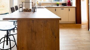 A modern kitchen with a central island, wooden flooring, pendant lighting, and a view of the outdoors through large windows. - Big Baron Holiday Home Bruges - Free parking (Brugge)