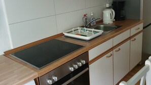 Et køkken med en Bosch ovn, en vask med sæbedispenser og en elkedel.