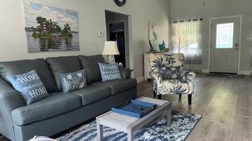 A living room with a dark grey sofa, floral patterned armchair, and a coffee table with a blue tray.