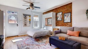 Un dormitorio con cama, ventilador de techo, cómoda y ventana grande.