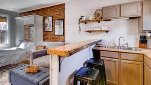 Un espacio habitable compacto con kitchenette, cama y zona de estar.