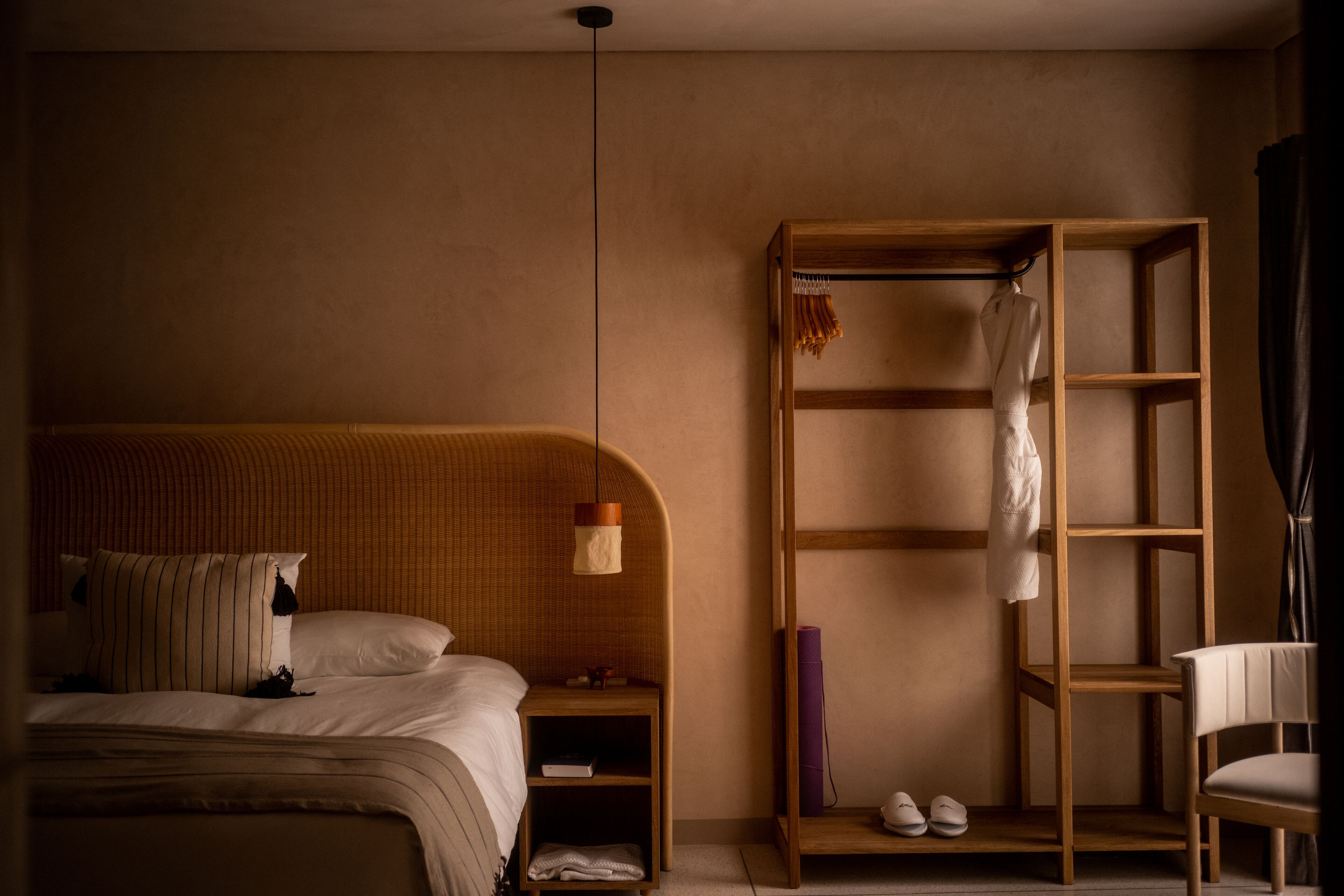 Un dormitorio con una cama, un armario de madera, una silla y un estante con zapatos.