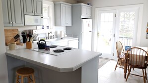 Une cuisine moderne avec des meubles blancs, un îlot central et un coin repas doté de chaises en bois.