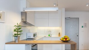 Una cocina moderna con armarios blancos, encimera de madera, microondas, fregadero y dos taburetes.