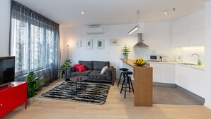 Una sala de estar moderna con un sofá gris, un mueble para televisión rojo y un tapete blanco y negro.