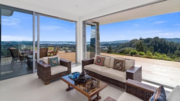 A modern living room with a large glass door leading to a balcony with a scenic view. - Tihi Retreat - Rotorua (Rotorua Township)