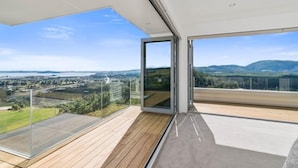 A modern balcony with a clear view of a landscape, including distant hills and a town. - Tihi Retreat - Rotorua (Rotorua Township)