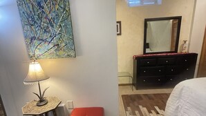 A bedroom with a bed, a red ottoman, a floor lamp, a painting, a dresser, and a mirror. - SPACIOUS  ONE  BEDROOM APARTMENT VERY CLOSE TO VENICE BEACH with washer /dryer (Los Angeles)