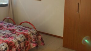 Quarto com cama, guarda-roupa e parede com pintura floral.