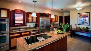 A modern kitchen with granite countertops, stainless steel appliances, and pendant lighting.